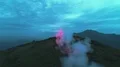The flight above the man with a firework stick on the mountain 4k or 4k+ Resolution