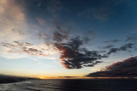 Flight above ocean waves facing beautiful sunset and mountains on horizon. Stock Photos