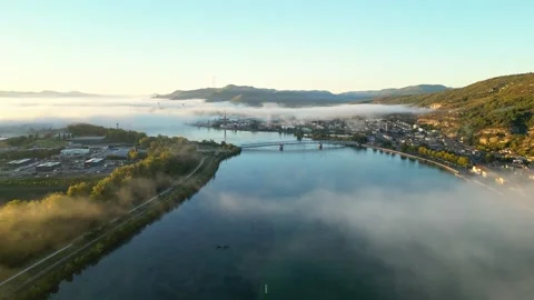 A flight along the Rhone River overlooking the town of Le Pouzin with thick fog Stock Footage 219964873