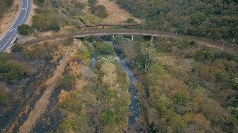 Flight along small river with old rail tracks crossing burnt bush on the left Stock Footage 78584575