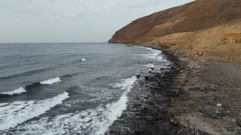Flight alongside rocky pebble beach and cliffs on the coast of Fuerteventura Spa Stock Footage 201786911