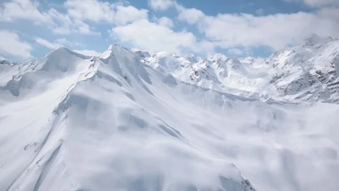 Flight around snowy peaks. Clouds and blue sky Stock-Footage 83713851