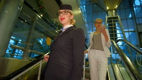 Flight attendant with glasses goes down the escalator and smiling Stock Footage 71636549
