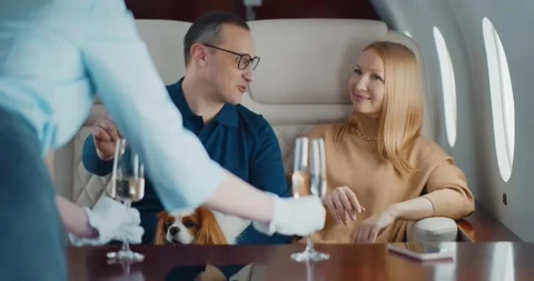 Flight attendant in private jet serving champagne glasses for happy couple with Stock Footage 151409988