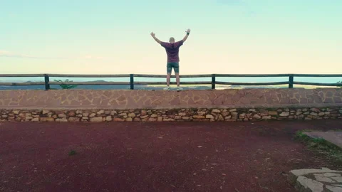 Flight from the back of a drone flying over a person leaning over a ravine Stock Footage 138895884