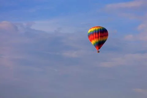 Flight of a beautiful multi-colored and motley balloon in the blue sky. Stock Photos