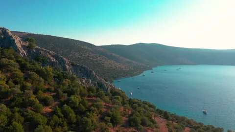 Flight from behind a crest of a cliff overlooking the bay. Dokos Island, Greece. Stock Footage 131015723