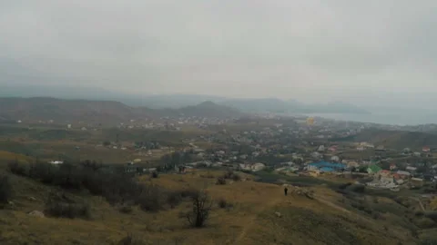 Flight of the camera over a hillside over a coastal village to the sea Stock Footage 86561871