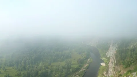 Flight of the copter through the fog on a river valley in the early morning. Stock Footage 114978302