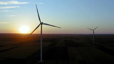 Flight by a couple of windmills on a large field with a sunset in the background Stock-Footage 138228685