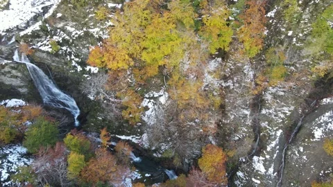 Flight descending over waterfall with snowy landscape and trees with autumn  Stock Footage 166199605