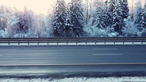 Flight of the drone parallel to the road, cars drive along the highway, winter Vidéo 163679157