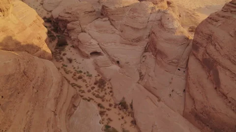 Flight dropping into canyon with caves, rock, desert. Sunset. Aerial 4K Stock Footage 196837833