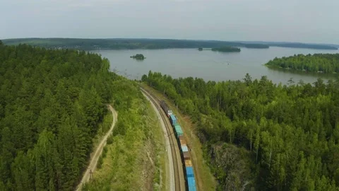 Flight for a freight train among the forest on the lake shore, nature of Urals Stock Footage 165343511