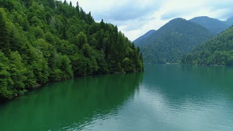 Flight large alpine blue glacial lake Ritsa mountains Georgia subtropical forest Stock Footage 128278071