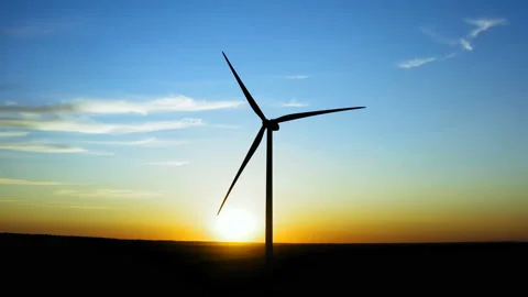 Flight by a large windmill with the sun setting in the background Видео 138228655