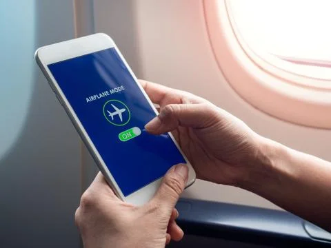 Flight mode concept. Hand holding white smartphone and turned on airplane mod Stock Photos