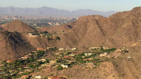 Flight over arid hills hiding pockets of residential areas to reveal Phoenix. Stock Footage 59523443