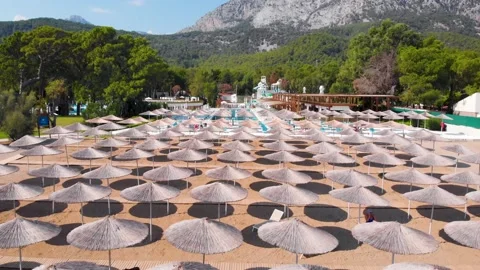 Flight over the beach with umbrellas towards the pool in a luxury hotel Stock Footage 195195414
