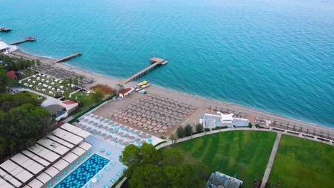Flight over the beach with umbrellas towards the pool in a luxury hotel Stock Footage 195195465