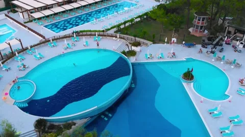 Flight over the beach with umbrellas towards the pool in a luxury hotel Stock Footage 195196014