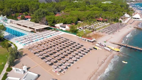 Flight over the beach with umbrellas towards the pool in a luxury hotel Stock Footage 195196138