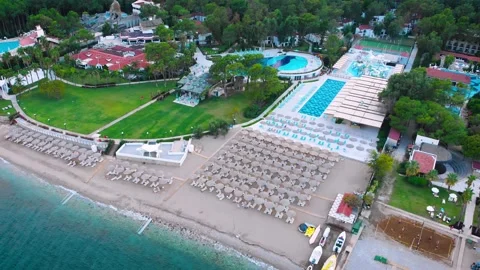 Flight over the beach with umbrellas towards the pool in a luxury hotel Stock Footage 195196260