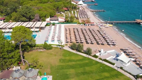 Flight over the beach with umbrellas towards the pool in a luxury hotel Stock Footage 195196502