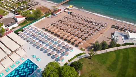 Flight over the beach with umbrellas towards the pool in a luxury hotel Stock Footage 195196579