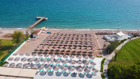 Flight over the beach with umbrellas towards the pool in a luxury hotel Stock Footage 195196865