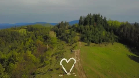 Flight over a big white heart on the top of the mountain Stockbeeldmateriaal 273586903