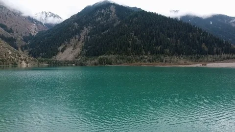 A flight over the blue water of the mountain lake Issyk. Stock Footage 79756827