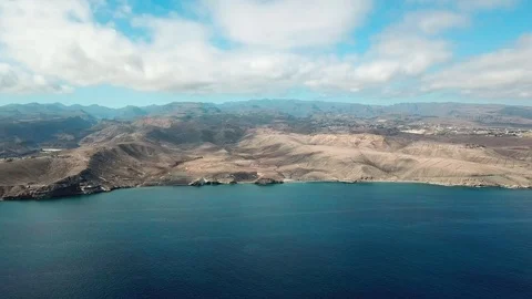 Flight over calm blue ocean and mountains. Top view of nature landscape with Stock Footage 94076171