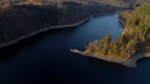 Flight over a calm river with an island in a hilly landscape full of forests Stockbeeldmateriaal 170547481