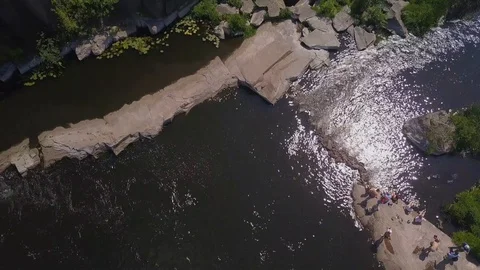 Flight over a canyon with a river with stone rapids and resting people Stock Footage 129497125