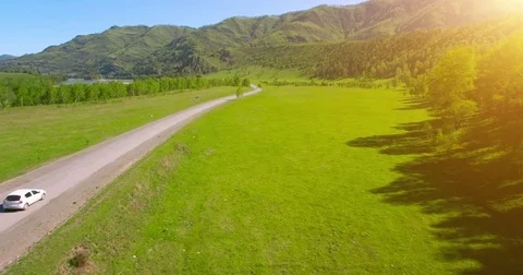 Flight over cars on a winding road in the hills and meadow. Rural highway below Stock Footage