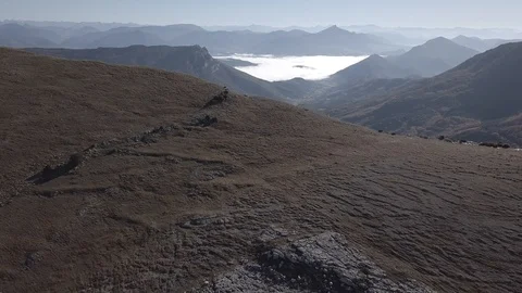 Flight over cliff, mountains and valley at sunrise  4k ungraded Stock Footage 105851261