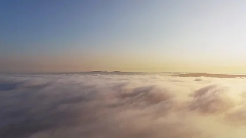 Flight over clouds and fog towards the sun and mountains on the horizon. Stock Footage 127170456