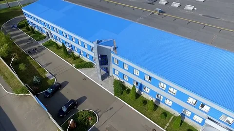 Flight over commercial building facade and village landscape HD aerial video Stock Footage 72219289