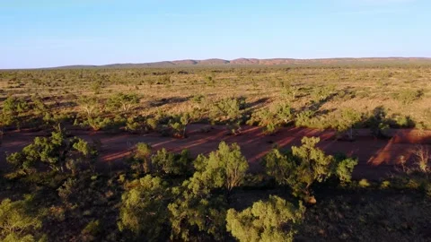 Flight over dry river bed towards mountain range at sunset Stock Footage 153968648