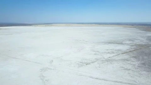 Flight over empty salt pan with blue horizon over the Kalahari desert Stock Footage 80988117