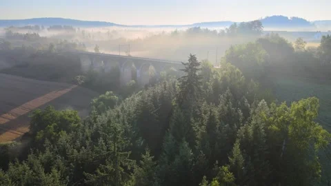 Flight over a field and forest in the morning fog near a railway viaduct. Stock Footage 294386501
