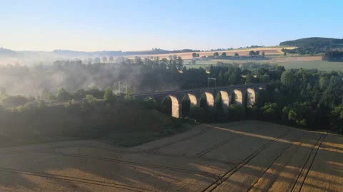 Flight over a field and forest in the morning fog near a railway viaduct. Stock Footage 294386785