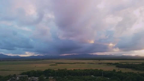 Flight over fields against backdrop of softly pink-purple sunset mountains Stock Footage 273533777