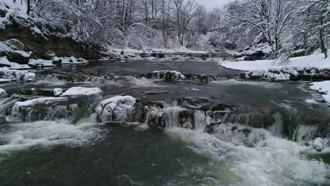 Flight over the flow of a mountain winter river on a cloudy day. Video stock 228994057