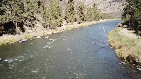 Flight over Flyfisherman at remote high desert flyfishing stream canyon Stock Footage 95875173