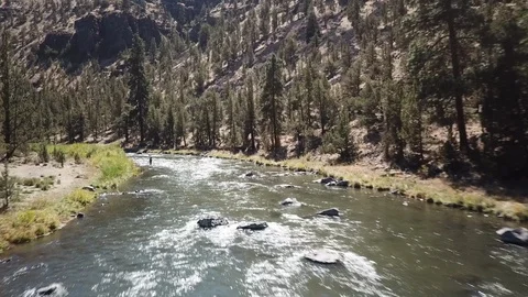 Flight over Flyfisherman at remote high desert flyfishing stream canyon Stock Footage 95875324