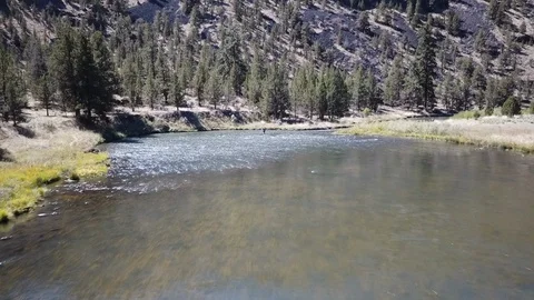 Flight over Flyfisherman at remote high desert flyfishing stream canyon Stock Footage 95875534