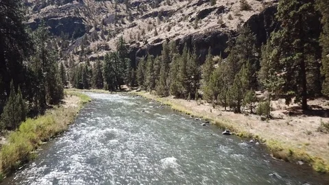 Flight over Flyfisherman at remote high desert flyfishing stream canyon Stock Footage 95876070