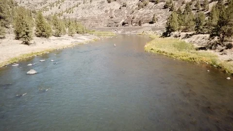 Flight over Flyfisherman at remote high desert flyfishing stream canyon Stock Footage 95877713